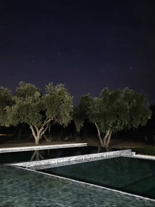 Pileta de noche bajo un cielo con estrellas