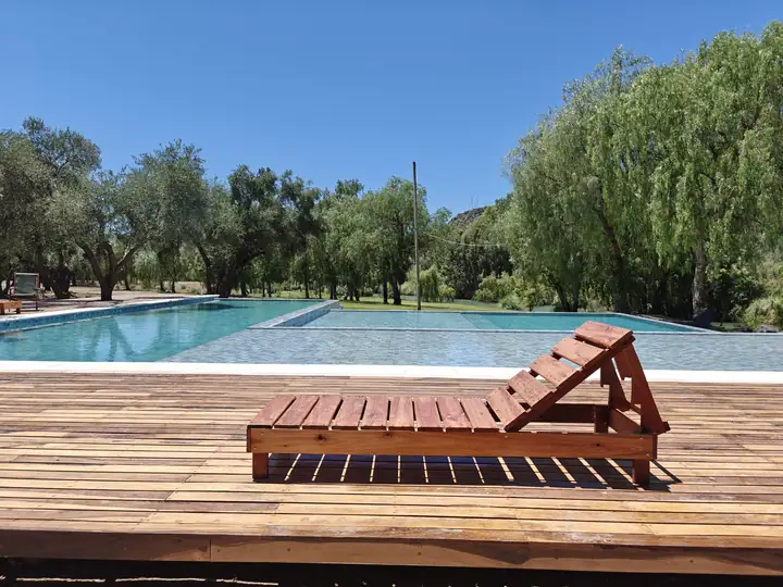 Reposera de madera sobre el deck de la pileta