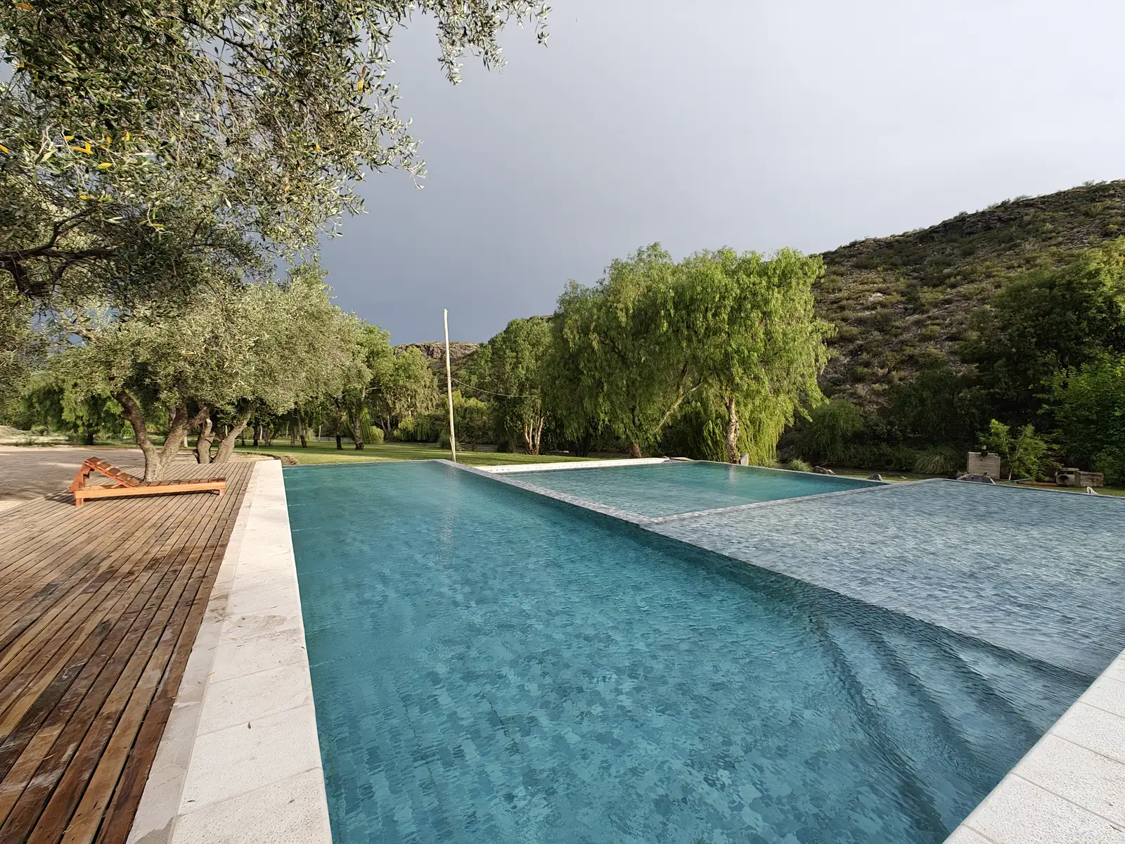 Pileta con deck de madera frente a los sauces y los cerros